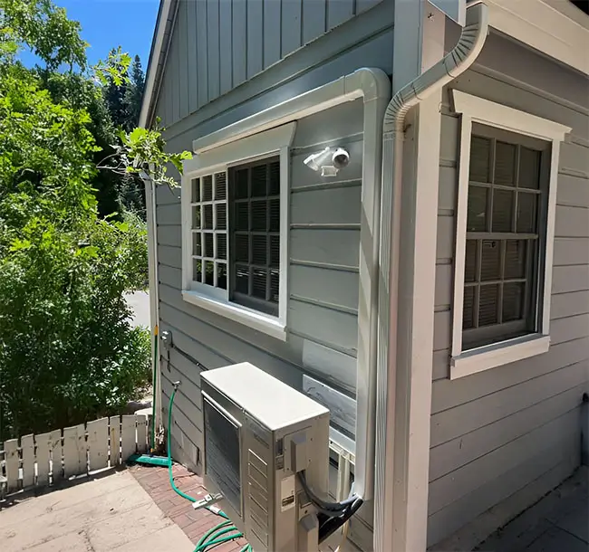 Ductless air conditioning system set up outside a tiny home on a sunny day.