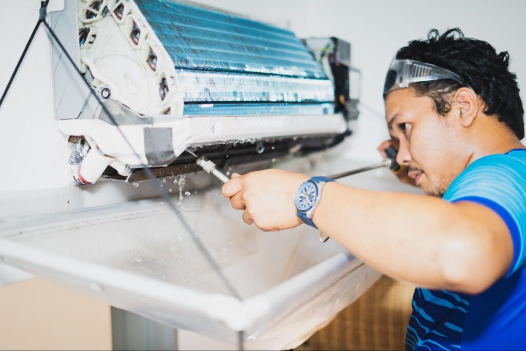 A technician performs AC repair services on an indoor unit.
