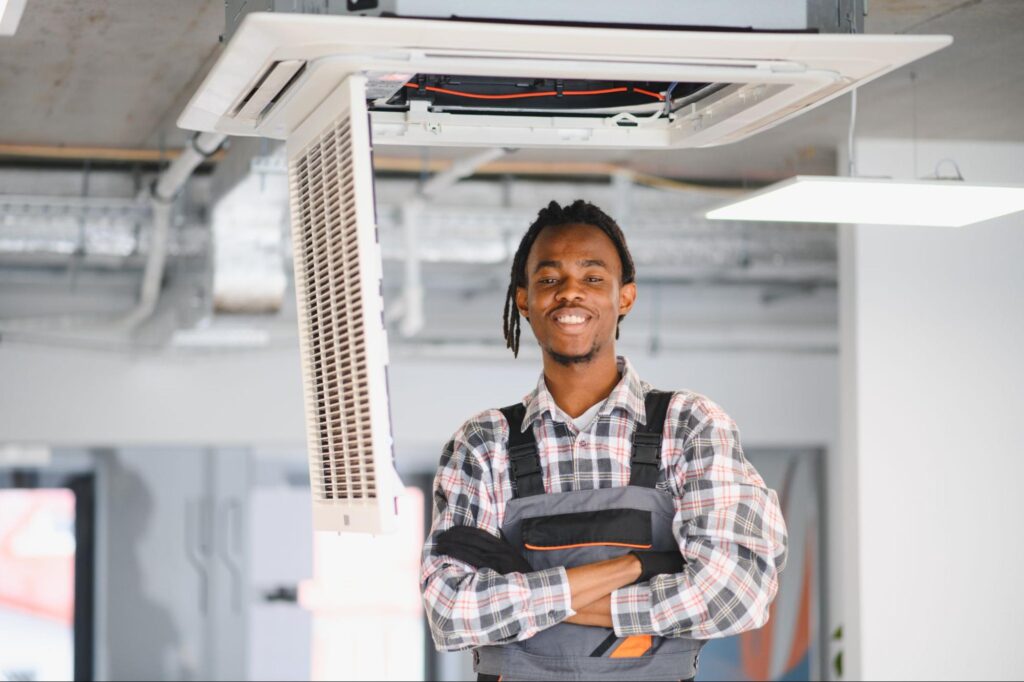 An HVAC technician installs an overhead AC unit.
