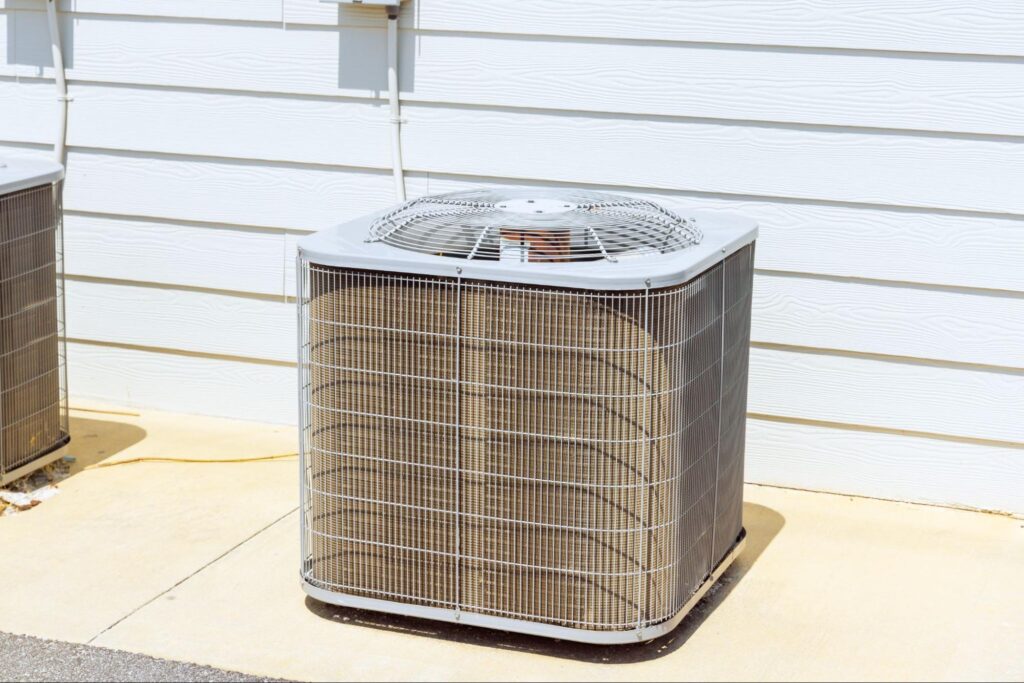A large central AC unit sitting outside a home.