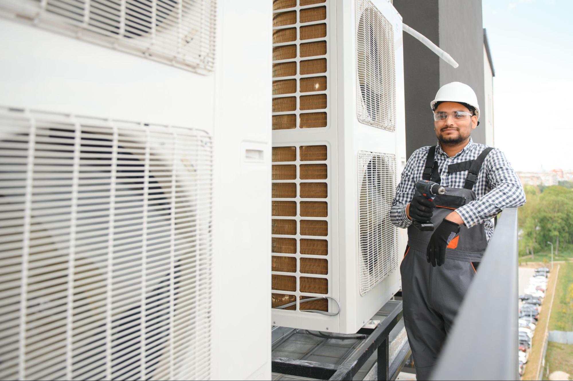 A repairman in uniform installs an outdoor AC unit.